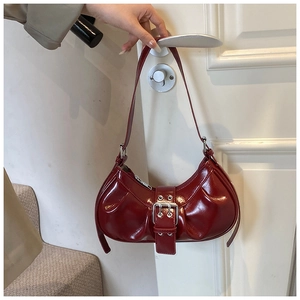 Detail of dark red patent leather dumpling bag with silver buckle and pleated texture