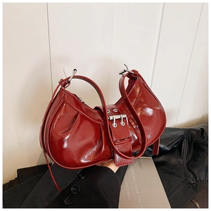 Close-up of wine red pleated crescent bag with high-shine patent finish and silver buckle