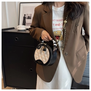 Détail du sac bandoulière rond matelassé avec poignée foulard et chaîne en métal