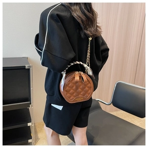 Détail du sac rond matelassé marron avec poignée en foulard de soie et chaîne dorée