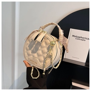 Détail du sac à main rond matelassé avec poignée en soie et bandoulière dorée