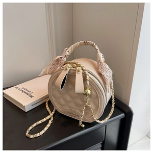 Détail du sac rond beige matelassé avec poignée en foulard et bandoulière chaîne