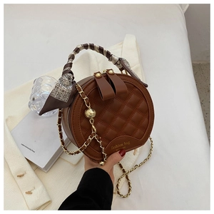Détail du sac rond matelassé marron avec poignée en foulard de soie et chaîne dorée