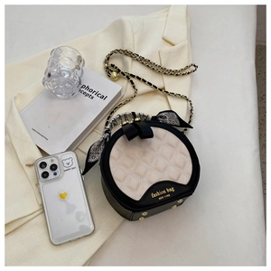 Gros plan du sac à main rond matelassé avec poignée en foulard sur un blazer beige