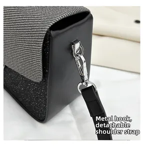 Detail of silver metal clasp and detachable black strap on textured crossbody bag