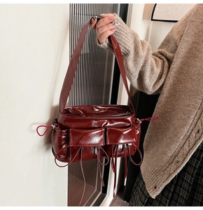 Détail du sac à bandoulière rouge brillant avec poches à rabat et détails de cordon de serrage