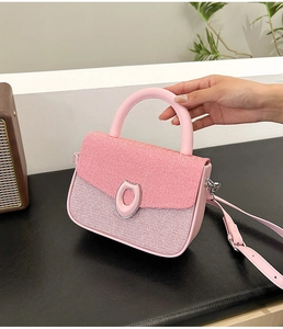 Detail of pink shoulder bag featuring textured flap and silver horseshoe metal buckle