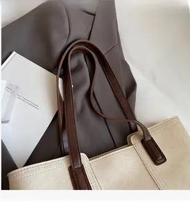 Close-up of minimalist cream tote bag with brown straps styled with a professional suit