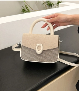 Detail of contrast stitching and bicolor woven texture on a modern crossbody bag