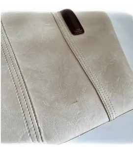 Detail of beige faux leather handbag with gold embossed lettering and neat parallel stitching