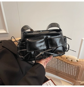 Vue détaillée du sac en cuir verni noir avec poches à cordon et garnitures métalliques