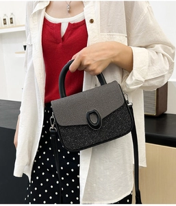 Detail of crossbody bag featuring grey fabric flap and black sequin base with horseshoe buckle