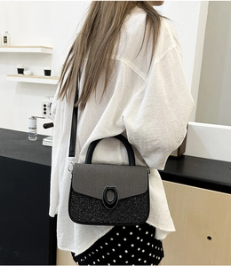 Detail of contrast stitch handbag with textured gray flap and black shimmering body
