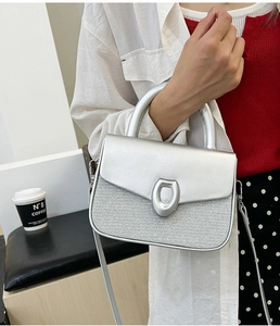 Detail of silver textured handbag featuring a shiny finish and oval metallic lock