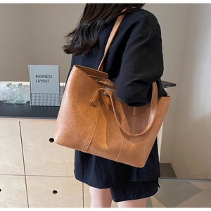 Detail of caramel leather tote bag with gold logo and premium vintage textured finish