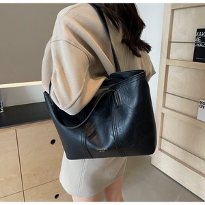 Detail of black tote bag with gold logo in home setting, showing retro leather texture