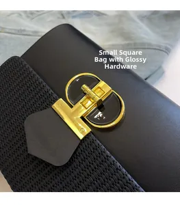 Detail of glossy hardware buckle on black leather and woven box bag over denim