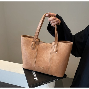 Detail of brown faux leather tote with gold-embossed logo and fine texture