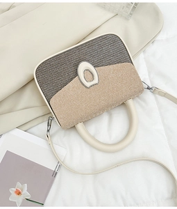 Detail of color-block crossbody bag with straw texture, cream leather, and oval buckle