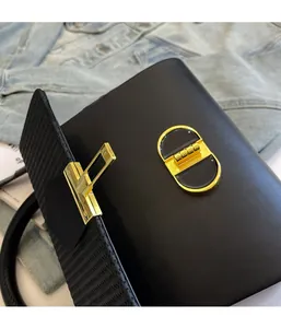 Detailed close-up of premium black leather handbag featuring a gold metal buckle closure