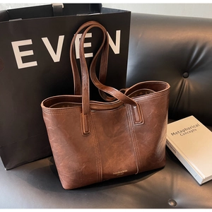 Detail of vintage dark brown tote bag with gold lettering on a black leather sofa