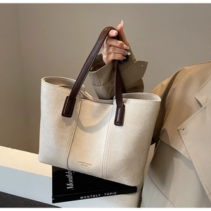 Detail of minimalist cream and brown tote bag with fashion gold text held by model