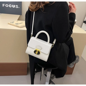 White leather handbag with woven texture and gold clasp shown on a shoulder model