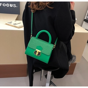 Close-up of green crossbody bag with woven texture flap and golden rotating metal lock