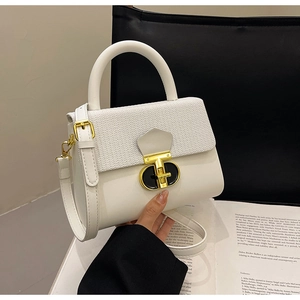 Detail of ivory white woven texture flap and gold metal clasp on a stylish handbag
