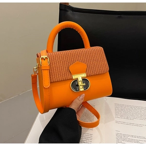 Detail of orange leather and straw patchwork handbag with gold metal lock closure