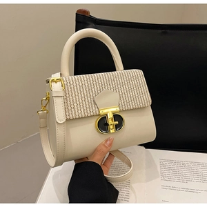 Detail of a creamy white handbag featuring woven texture and black-gold metal rotary lock
