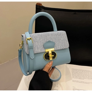 Close-up of blue pebbled leather handbag with tweed flap and gold twist lock