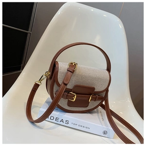 Detail view of canvas and brown leather stitching on a retro saddle shoulder bag