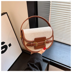 Detail view of canvas saddle bag with brown leather trim and golden metal buckles