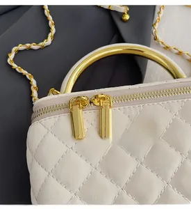 Detailaufnahme der goldenen Reißverschlüsse und des Blumenanhängers am weißen Shopper