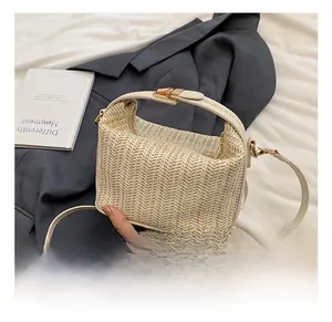 Close-up of beige woven straw handbag featuring herringbone texture and gold buckle detail