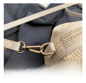 Detailed macro view of woven straw shoulder bag with durable gold metal swivel hooks