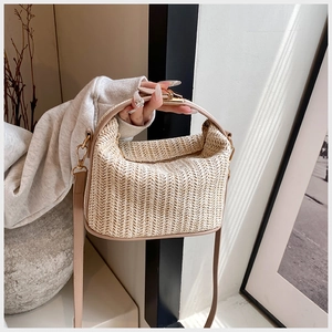 Detail of straw woven handbag with leather handles and metallic buckle in a lifestyle setting