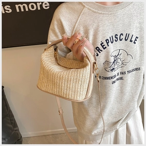 Detailed close-up of woven straw texture and beige leather trim on a summer crossbody bag