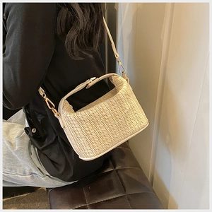 Detailed close-up of cream straw woven bag with gold hardware and leather strap