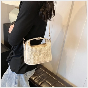 Close-up of beige woven straw handbag featuring V-shaped texture and leather strap