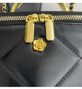 Detail of quilted leather handbag with gold camellia logo and double zip closure