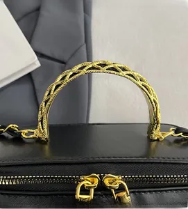 Close-up of elegant gold woven metal handle and double zippers on black leather box bag