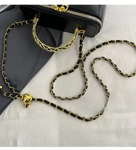 Close-up of black quilted box bag with golden chain strap and ball adjustment buckle