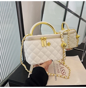Detail der gesteppten Box-Tasche mit goldenem Halbkreisgriff und Kettenriemen
