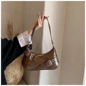 Detail of coffee brown retro baguette bag featuring silver buckles and eyelet straps