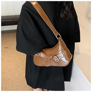 Close-up of vintage brown shoulder bag with buckle straps and metal eyelets on model