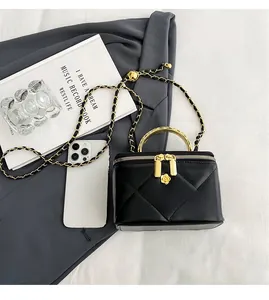 Detail of quilted leather box bag with gold metal handle and chain strap on grey blazer