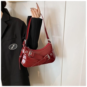 Detail of dark red patent leather shoulder bag with silver eyelets and buckle accents