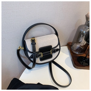 Canvas and black leather saddle bag with gold metal buckles and a top handle